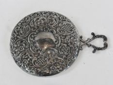 An Edwardian silver circular handmirror, with foliate and C-scroll repousse decoration, London 1901