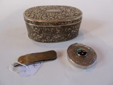 A white metal oval box with hinged cover and foliate scrollwork design together with a white and
