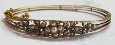 Gold coloured metal pearl and diamond pierced bangle, set with seedpearl flowerhead flanked by