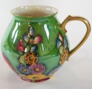 Carlton ware jug, lustre, hollyhocks on a green lustre ground, with gilt handle and gilt rim, 18cm