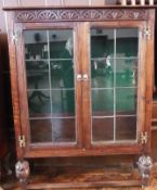 Oak display cabinet having two shelves enclosed by leaded glazed doors on carved cup and cover style