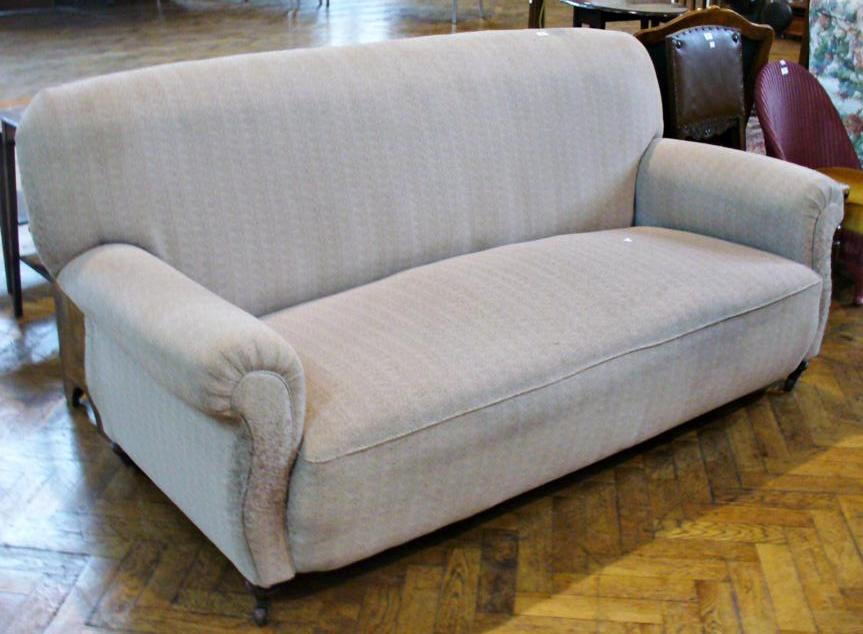 Late nineteenth century four seater sofa, stone coloured upholstery on turned legs with castors,