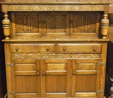 Reproduction oak court cupboard, the top with scroll carved frieze on foliate cup and cover carved