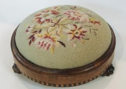 A late Victorian walnut circular footstool with upholstered needlework top, on veined glass feet