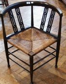 A stained beech corner chair with pierced splats, rush seat, on turned legs united by stretchers