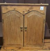 An old pine wall cupboard, the pair arched panelled doors enclosing shelf, 56cm wide