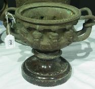 19th century bronze Warwick pedestal urn, mask embossed with entwined handles and on marble base, 20