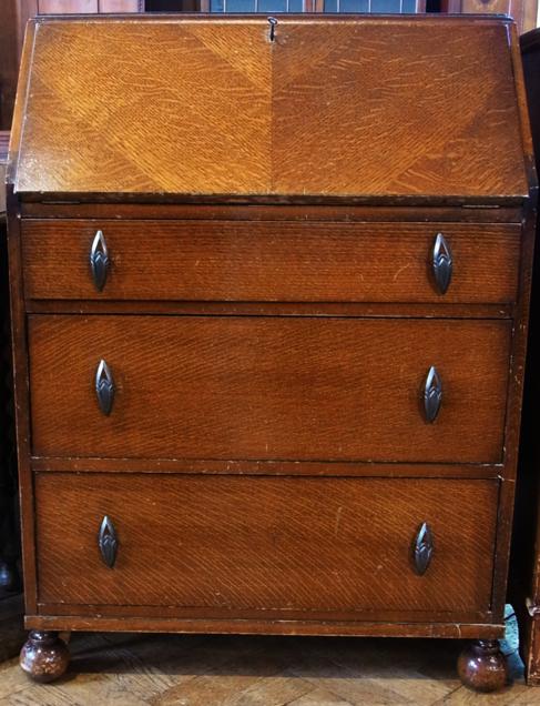 A reproduction oak bureau, the fall front enclosing fitted interior with three long graduated