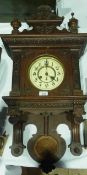 A late Victorian wall clock with carved foliate pediment with finials, enamelled dial, striking