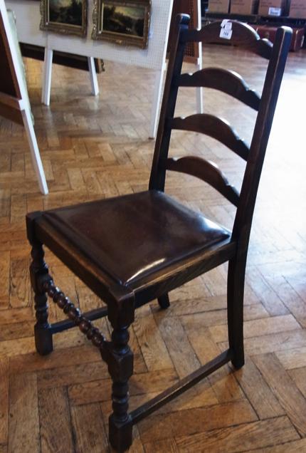 A set of four stained oak leatherette dining chairs with drop in seats, bobbin turned legs united by