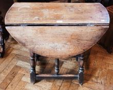 Old oak drop leaf oval topped table on turned baluster supports united by stretchers, width 76cms