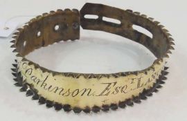 An 18th century brass dog collar with serrated edges, adjustable fitting, engraved with "Thos.
