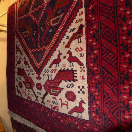 A fine North East Persian Meshed Belouch rug with repeating diamond shaped medallions with animal
