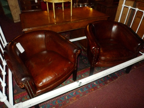 A pair of tub form library chairs upholstered in tobacco brown leather