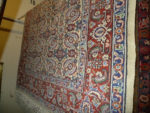 A Greek wool rug with repeating floral motifs on an ivory field surrounded by one frieze and two