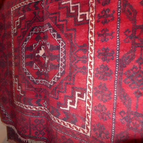 A fine old North East Persian Turkoman rug with repeating Goul motifs on a rouge field within