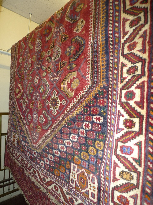A hand knotted Persian Qashgai rug the red field with geometric design within a stylized border W