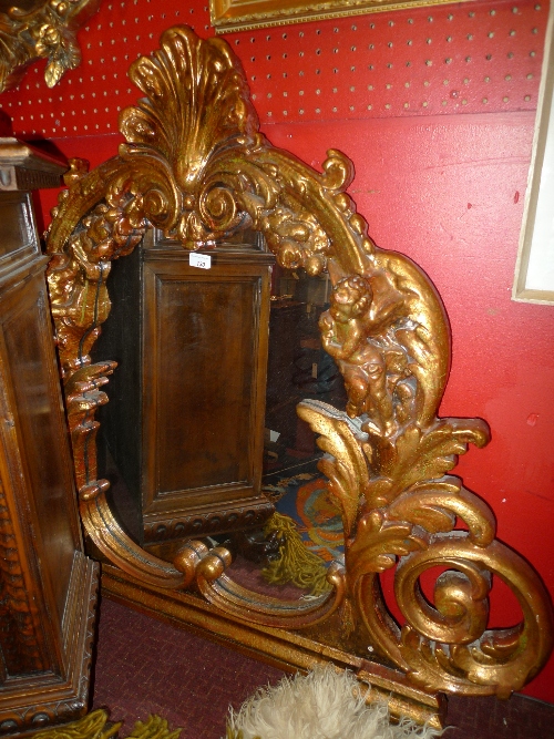 A French design overmantle mirror the shaped plate in  Rococo style gilt frame having cherubs in