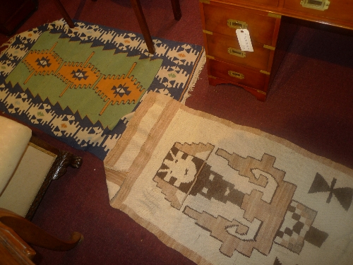 A contemporary woolen Kelim rug with geometric motifs on a green field together with a contemporary