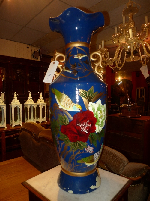 A blue enamel twin handled vase with painted flowerheads and stylized leafy detail H 80 cm