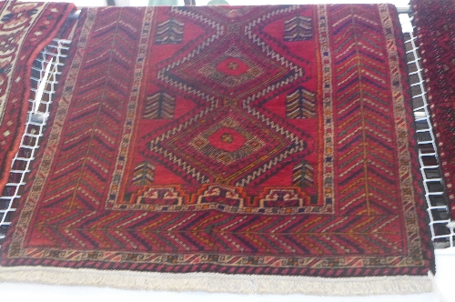 A fine North East Persian Kurdie rug repeating diamond shaped lozenge on a rouge field within