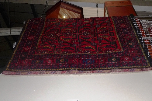 A fine North West Persian Kurdish carpet repeating perpadil motifs on a rouge field within multi