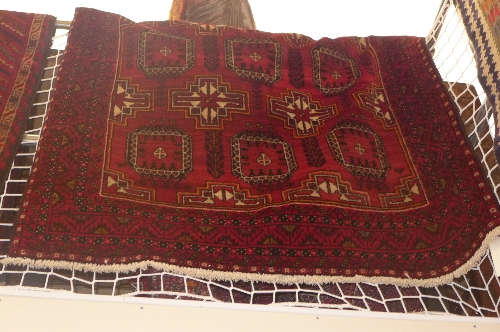 A fine North East Persian Turkoman rug repeating ghoul motifs on rouge field within stylized butter