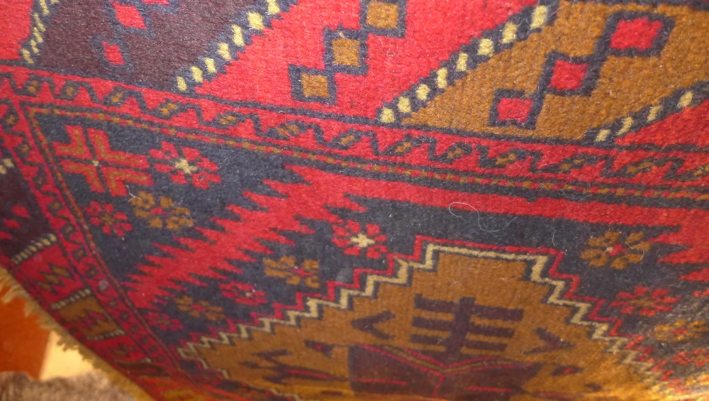 A hand knotted Persian Belouch rug the red field with triple pole medallion and geometric border