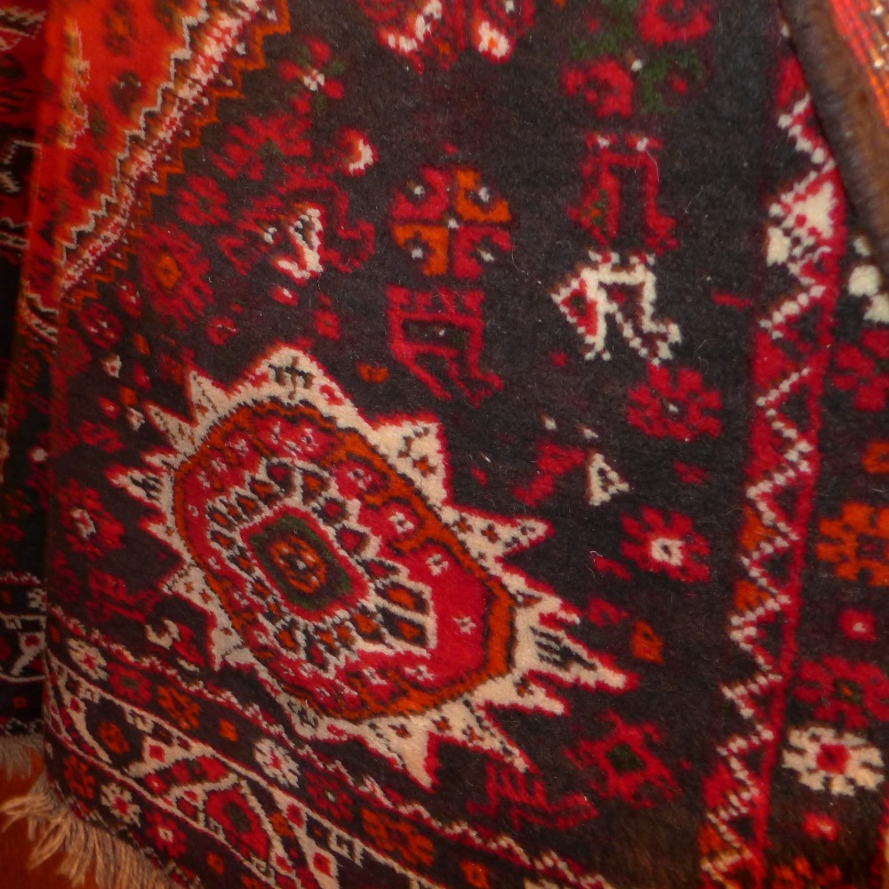 A hand knotted Persian Qashgai carpet the red field with central medallion and geometric design