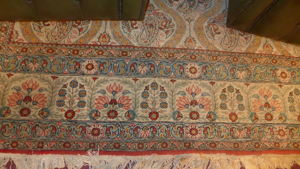 A large Persian carpet with a repeated motif to the centre on an ivory field surrounded by one