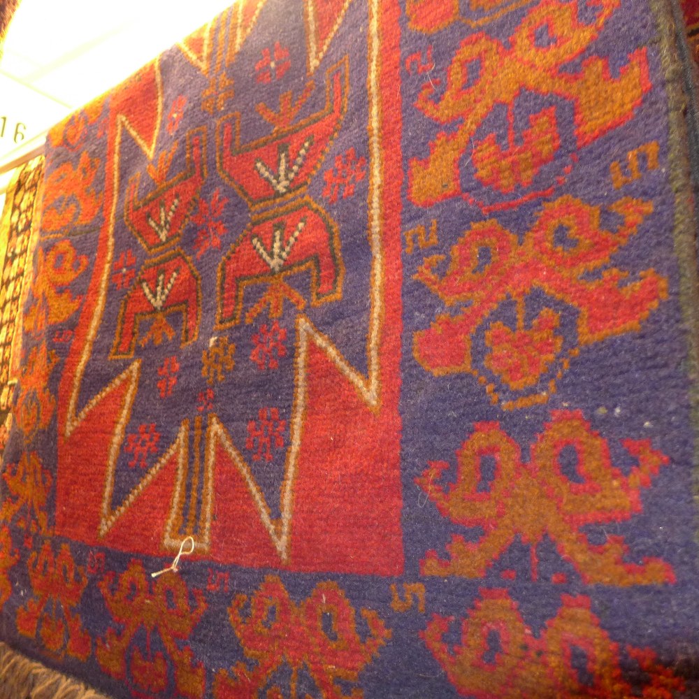 A hand knotted Persian Belouch rug the red field with bookcover design  142 x 81 cm