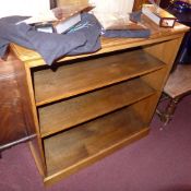 An ash open bookcase with adjustable shelves rasied on a plinth base