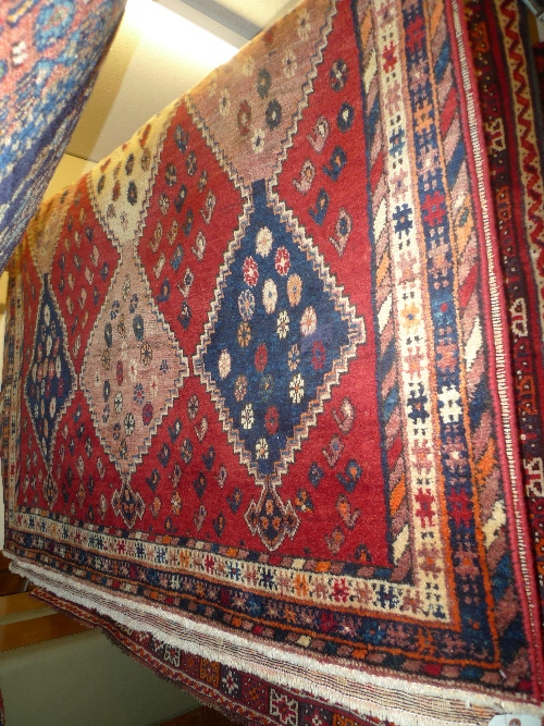 A hand knotted Persian Shiraz rug the red field with repeated diamond motifs within a stylized