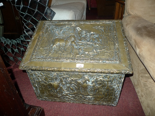 A brass coal box of sloping form with embossed figure decoration