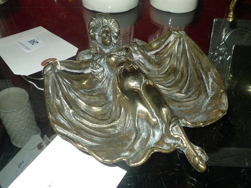 A brass ashtray with images of a well dressed lady