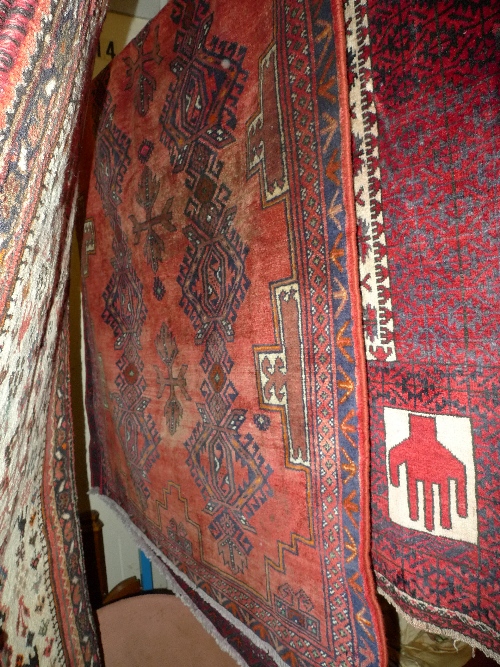 A fine North East Persian rug 252 cm x 116 cm with repeating floral motifs on a rouge field within