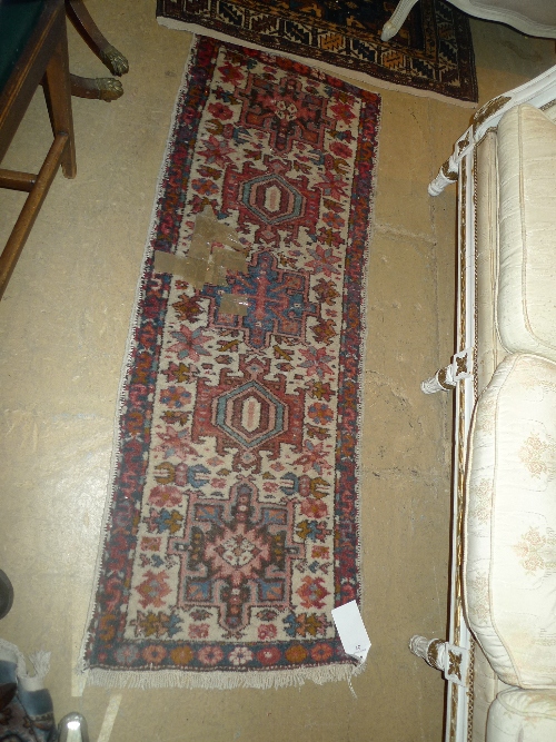 A hand knotted Persian style runner with central medallions on beige field within single border