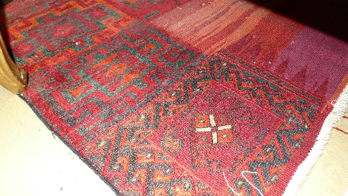 A hand knotted rug the red ground with geometric motifs