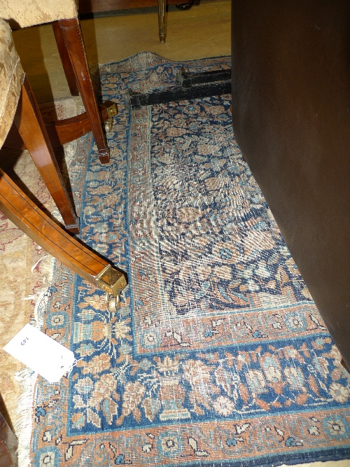 A Persian rug with beige background and blue stylized pattern