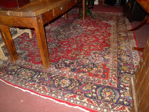 A hand knotted Persian carpet the red field with all over foliate decoration within a stylized