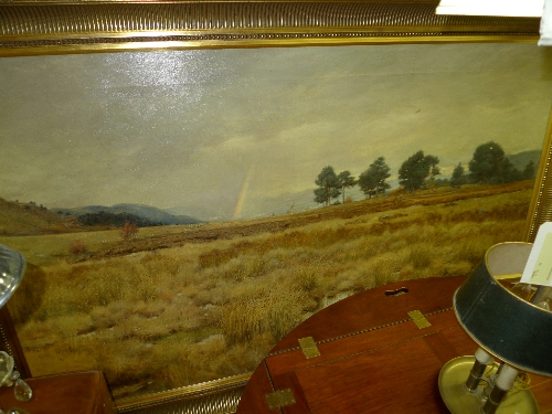 A large oil on canvas rural landscape with rainbow in the distance signed lower right within gilt