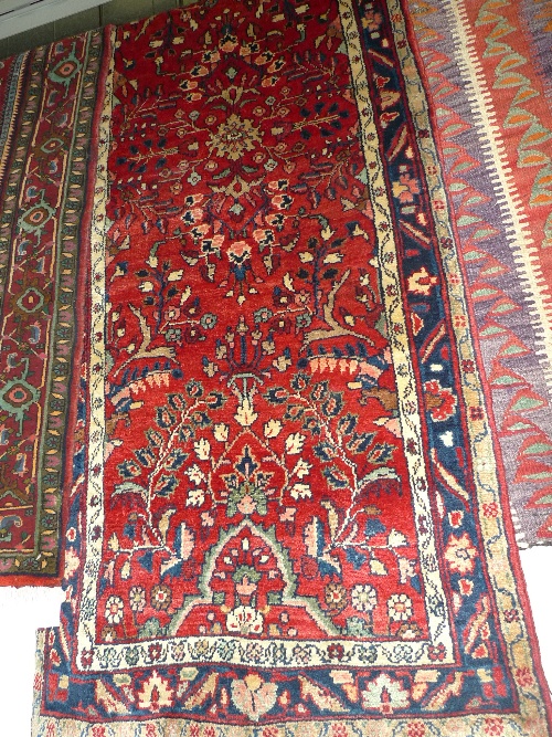 A fine North West Persian Sarouk runner 408 cm x 85 cm repeating floral motifs on a rouge field to