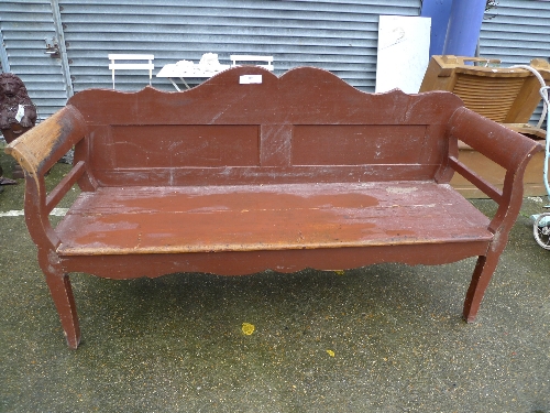 A brown painted garden bench with serpentine back