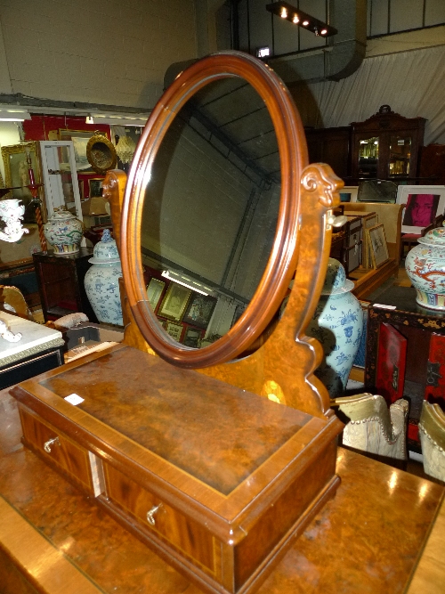 An inlaid walnut dressing mirror with oval plate above base drawer