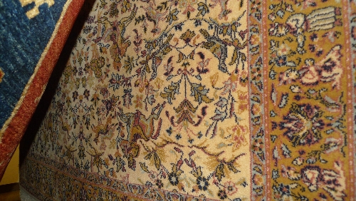 A Persian carpet with a floral and zoomorphic motif on an ivory field surrounded by a border