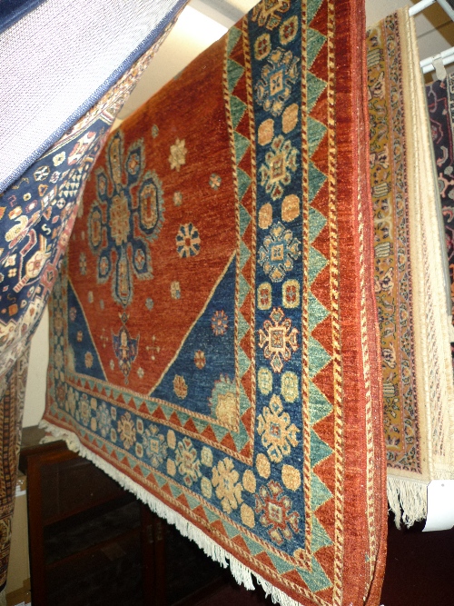 A fine Kazak rug with central pole medallion on a terracotta field with floral border 228 cm x 169