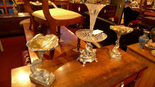 A white metal table garniture including a centre piece with a stylized dolphin base together with