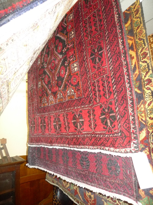 A fine North East Persian Meshed Belouch rug with repeating panel motifs on a midnight field
