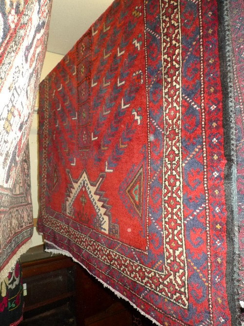 A fine North East Persian Zabul Belouch rug with repeating geometrical motifs on a rouge field