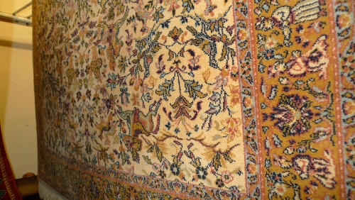A Persian carpet with a floral and zoomorphic motif on an ivory field surrounded by a border